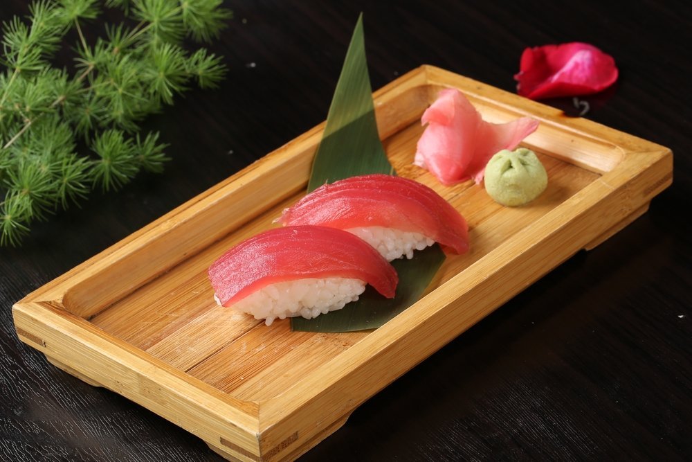 Sushi s tuňákem na rýži podávané s wasabi a zázvorem na dřevěném podnose
